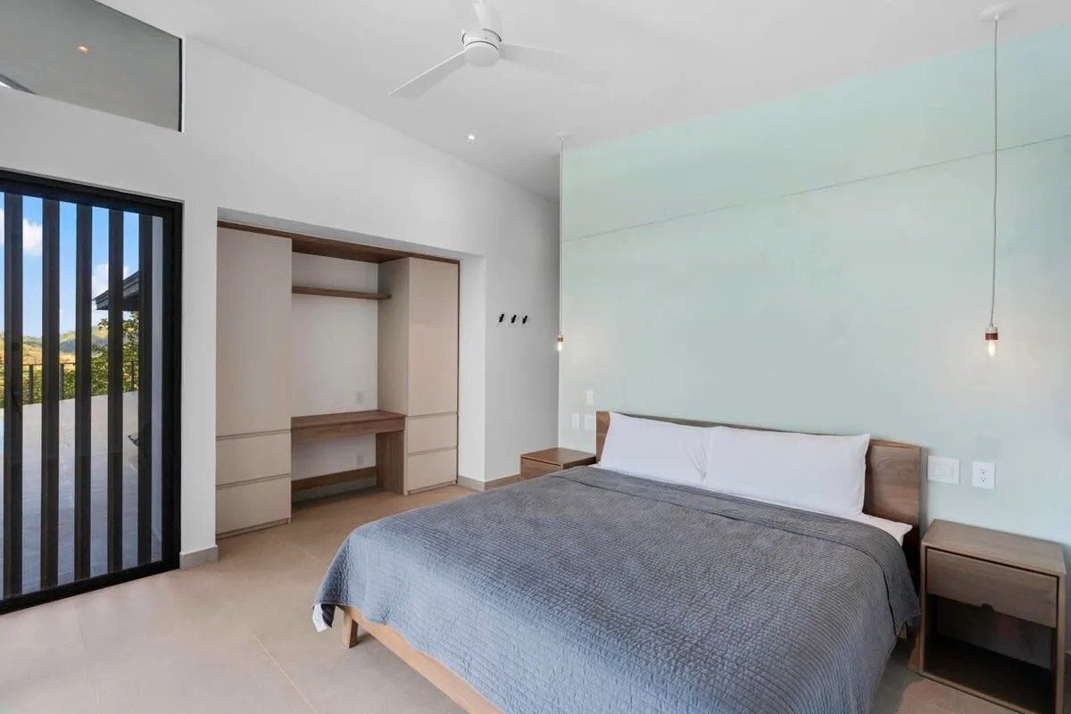 A bedroom with a bed, built-in shelving, and a sliding glass door.