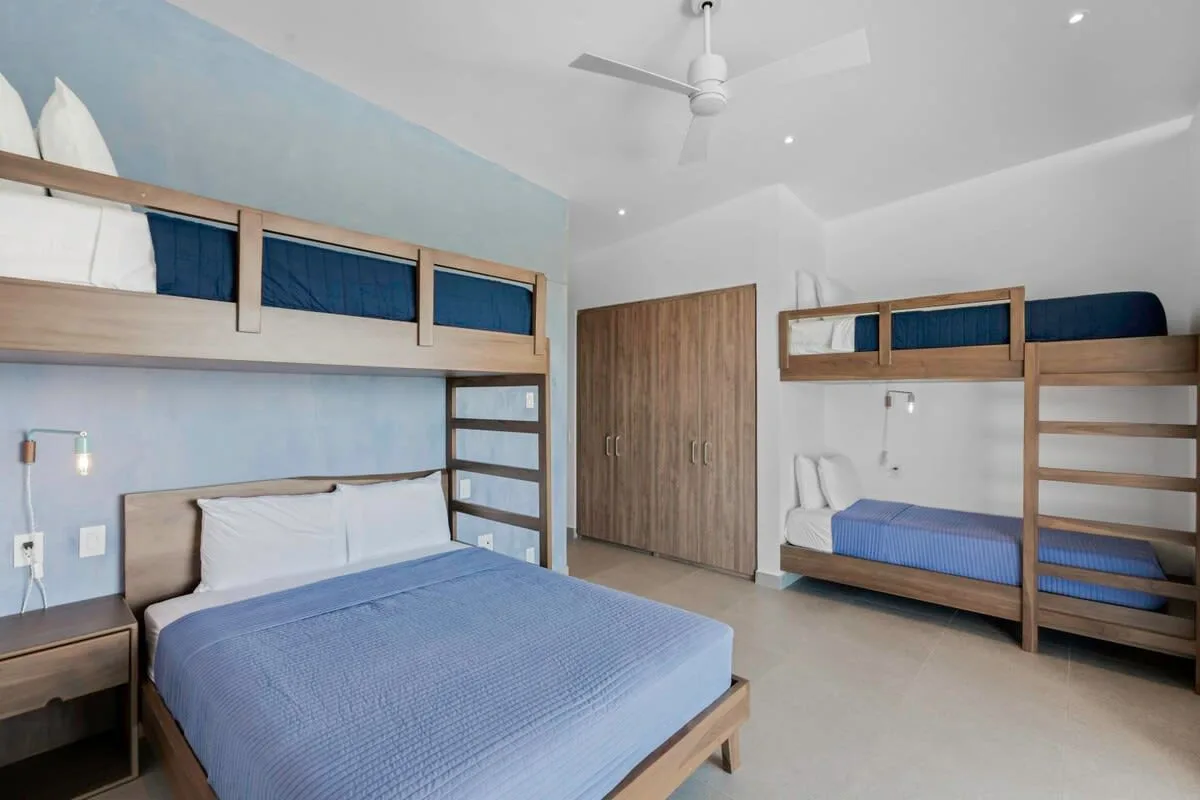 A bedroom with a large bed and a wooden bunk bed.