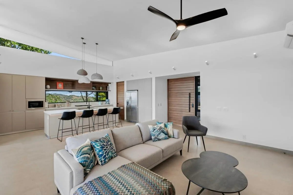 An open-plan living room and kitchen with a sofa and breakfast bar.