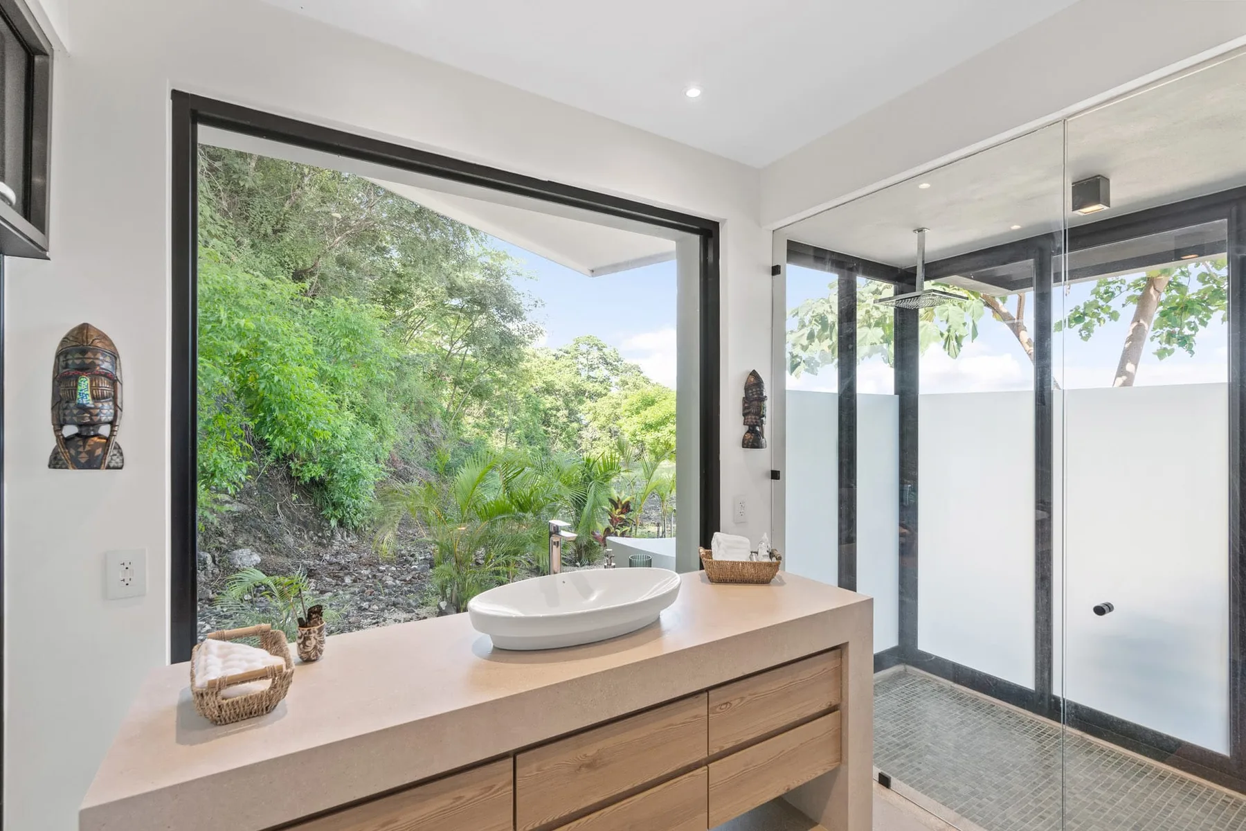 A bright bathroom features a wide vanity beside a glass-enclosed shower.