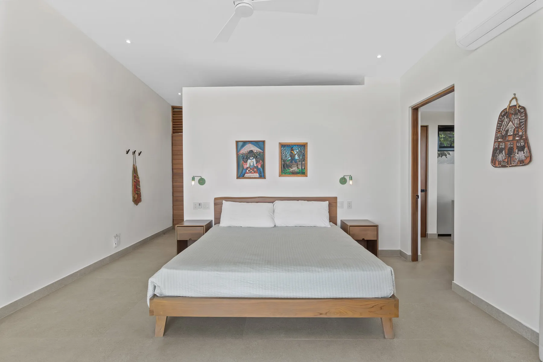 A bedroom with a neatly made bed and framed artwork above the headboard.