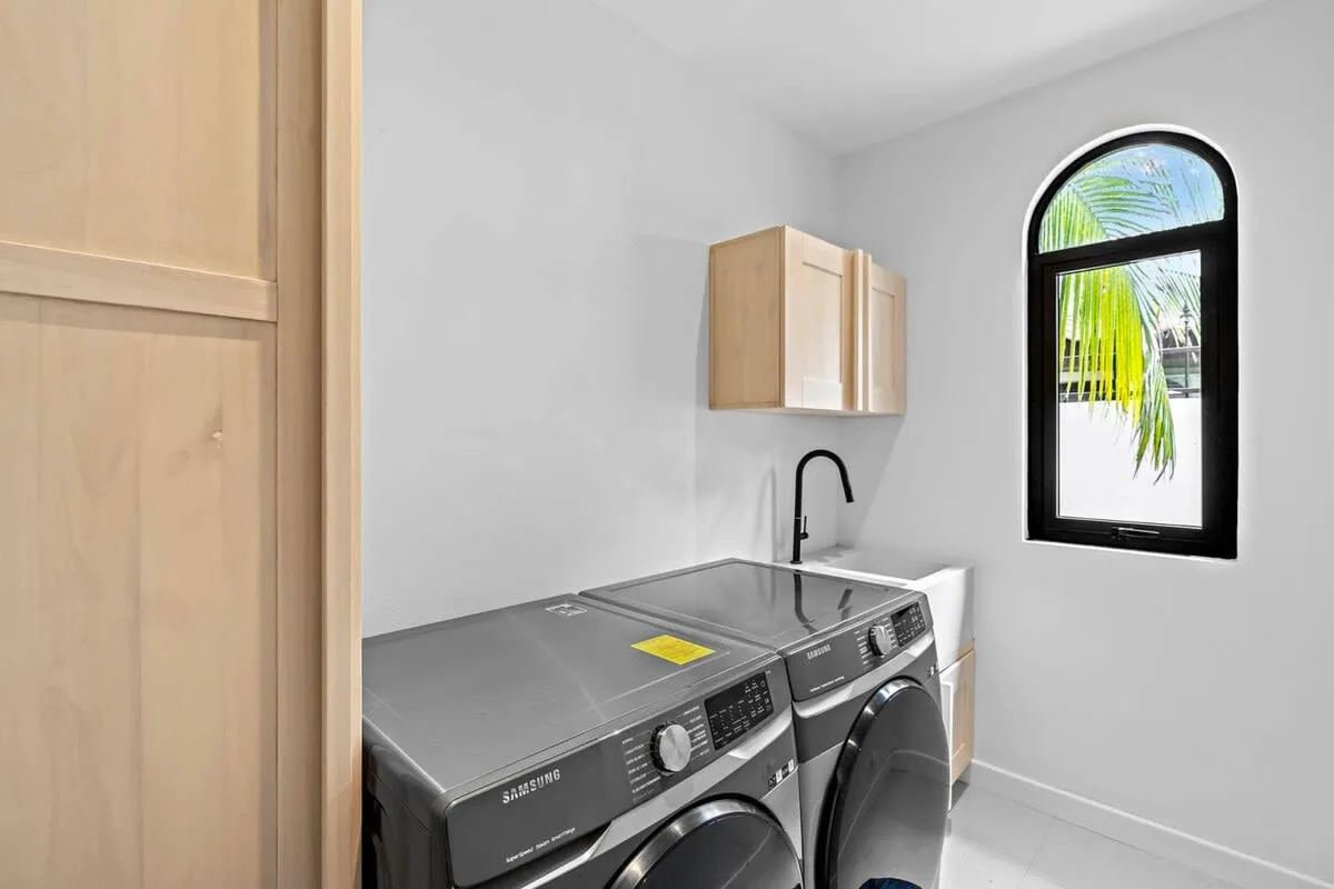 Laundry room with two front-loading machines beneath a wall-mounted cabinet.