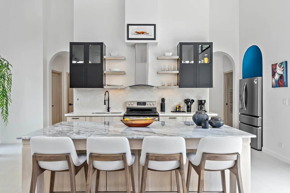 A bright kitchen with a central island, countertop seating, and dark cabinets.