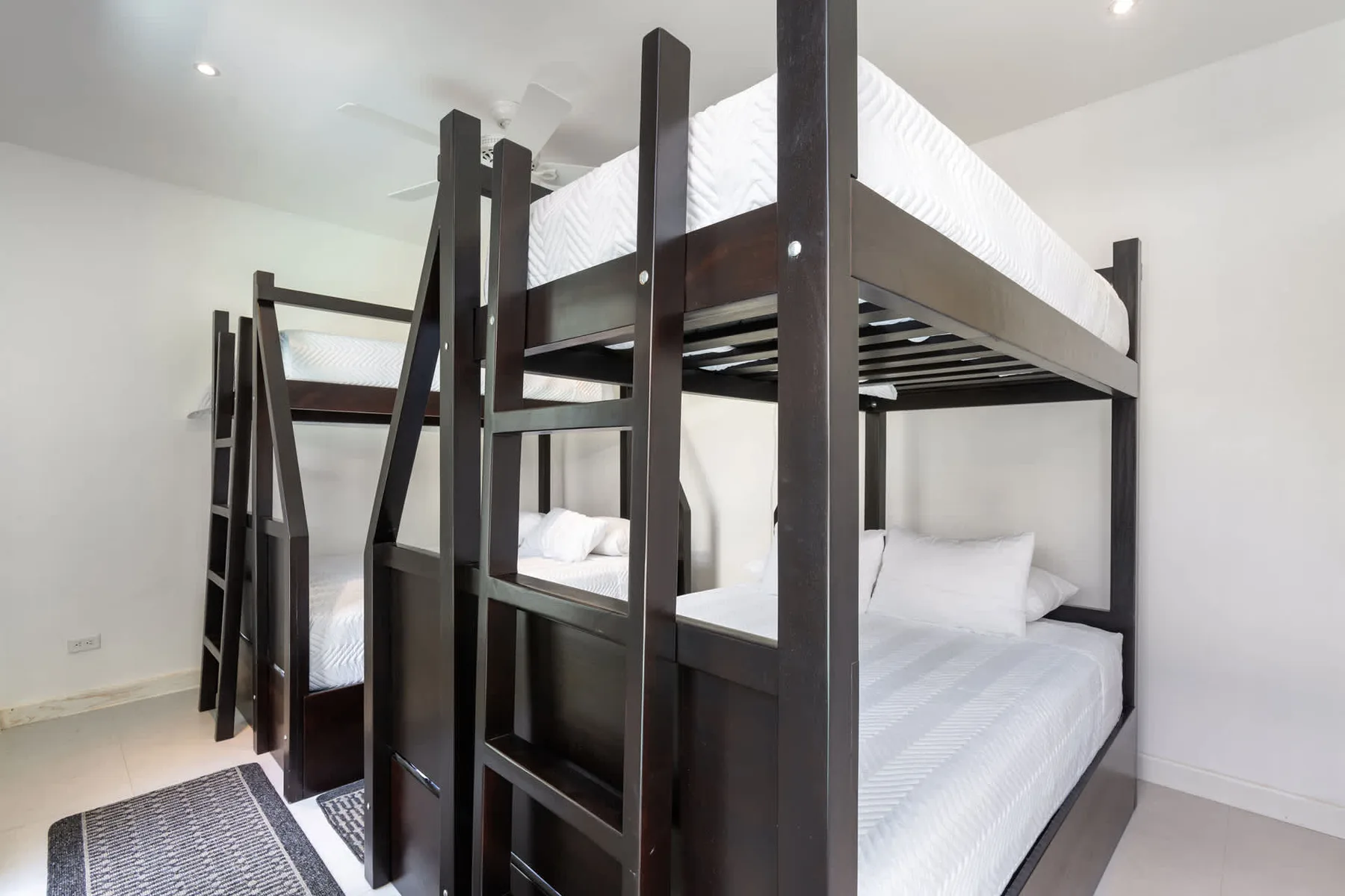 A bunk bed setup with dark frames and white bedding in a bright bedroom.