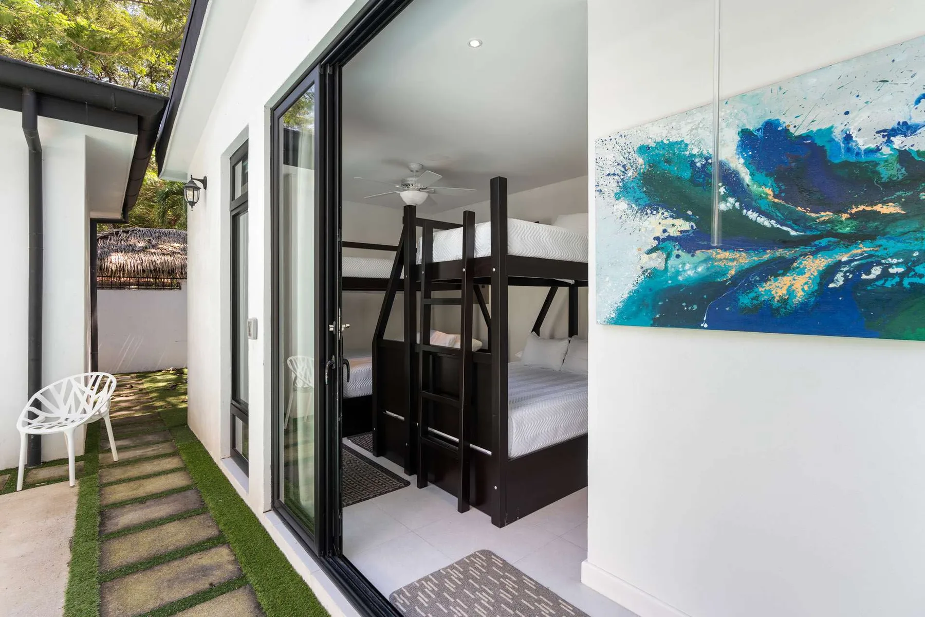 A bedroom with bunk beds is visible through the open sliding glass doors.