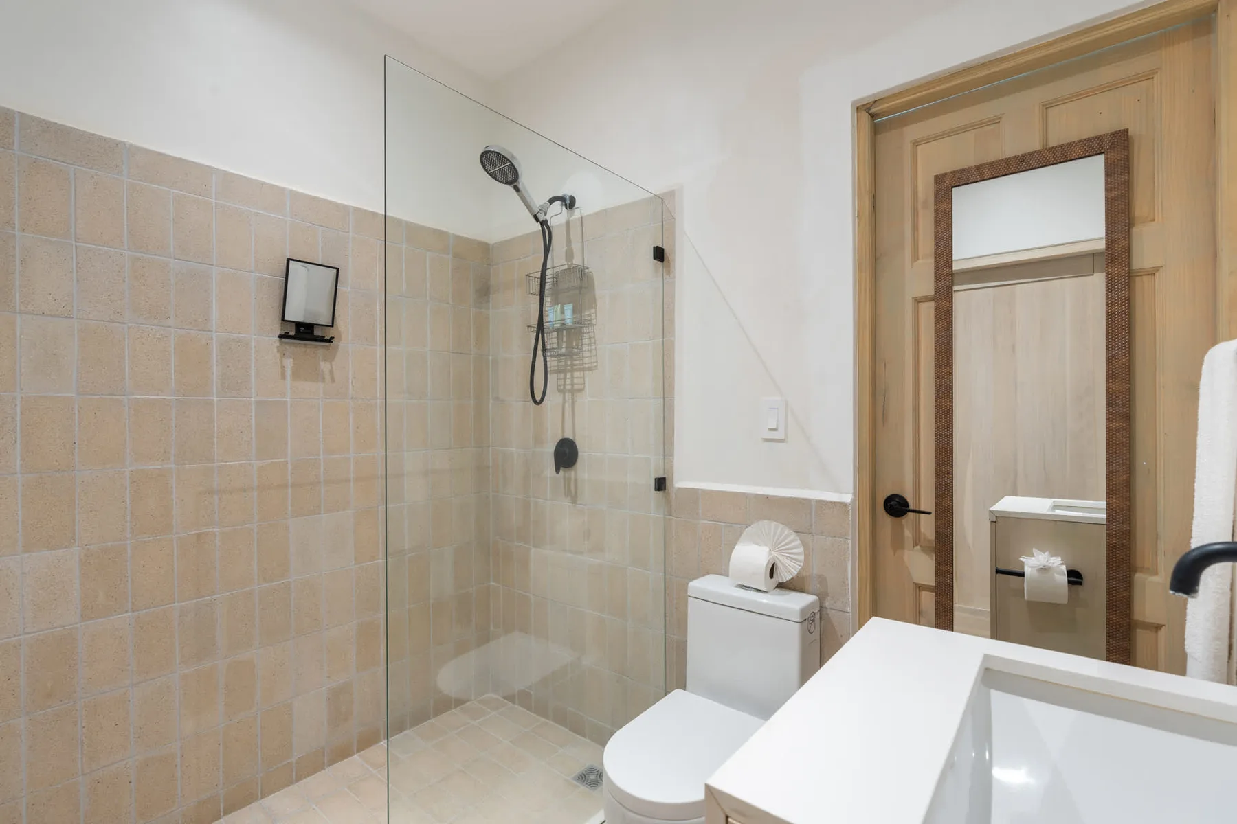 A bathroom with a glass shower, toilet, and sink.