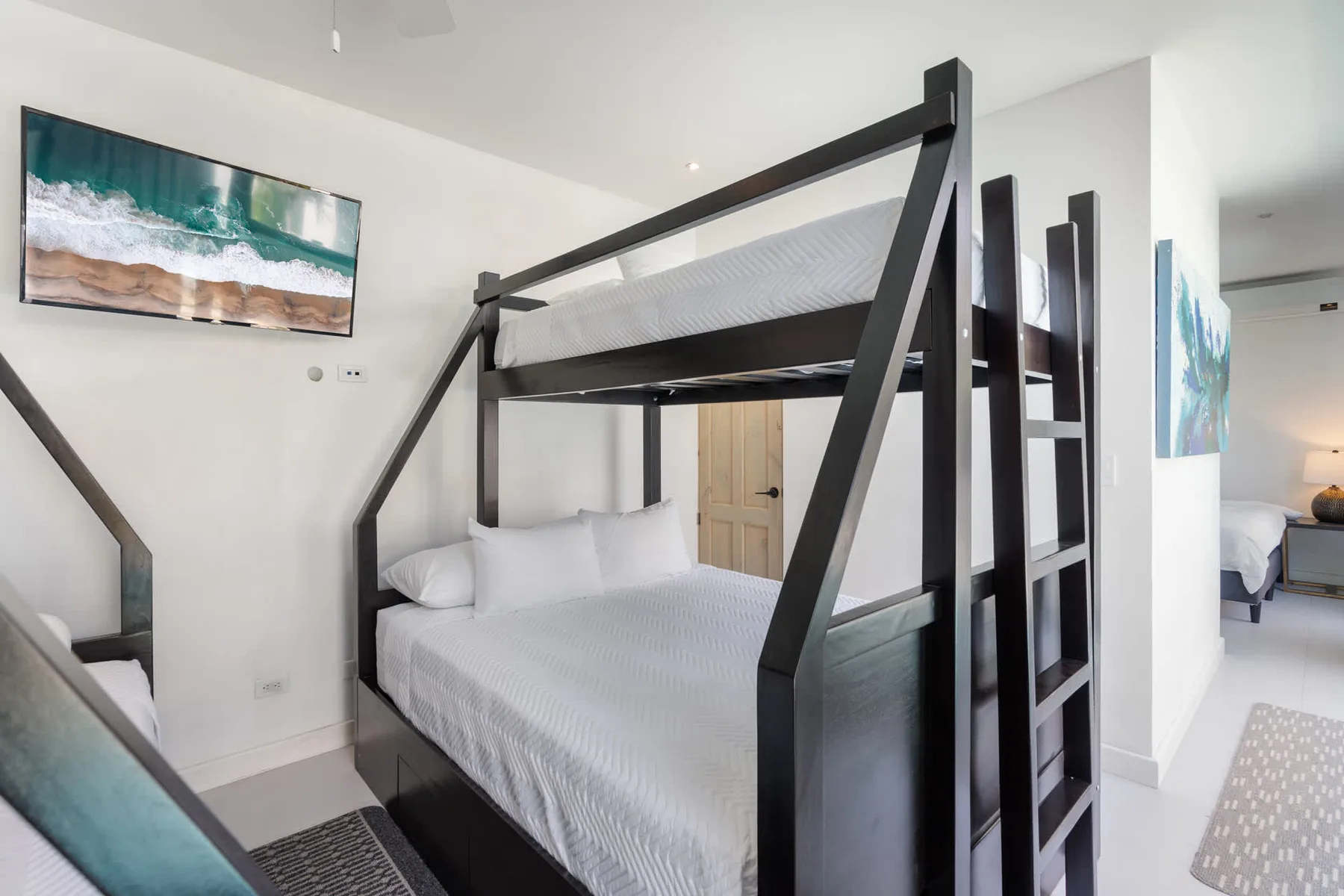A bedroom with a black bunk bed, white bedding, and framed artwork.