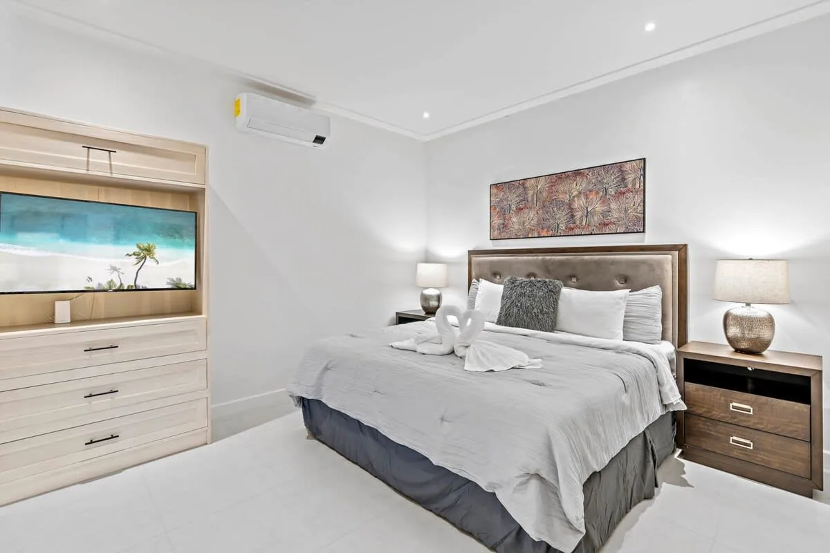 A bright bedroom with a neatly made bed and matching bedside lamps.
