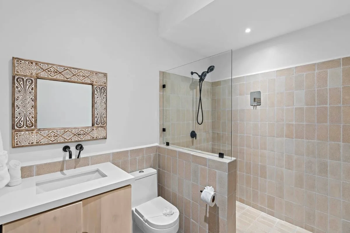 A bathroom with a vanity, toilet, and glass shower screen.