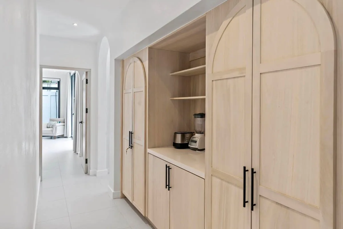 A bright hallway with pale wood cabinetry and open shelves along one wall.