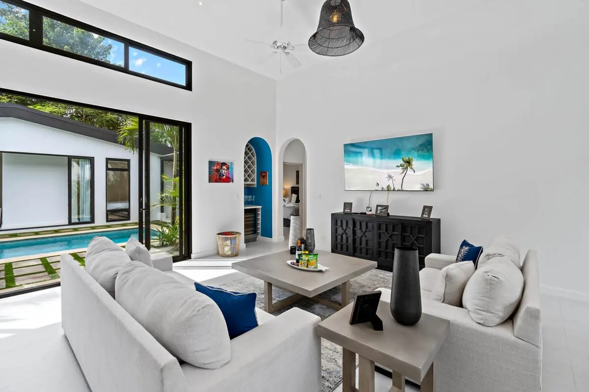 A bright living room with seating around a coffee table beside large windows.