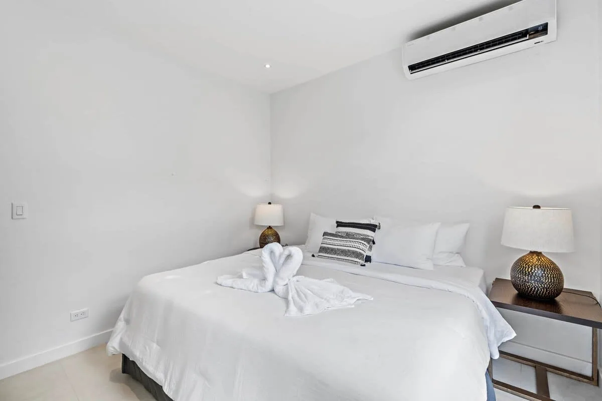 A bright bedroom with a neatly made bed and bedside lamps.