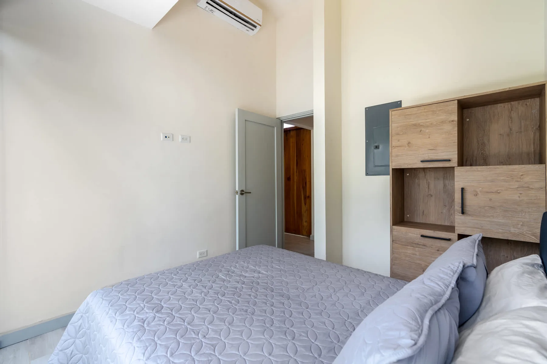 A bedroom with a bed and built-in wooden storage.