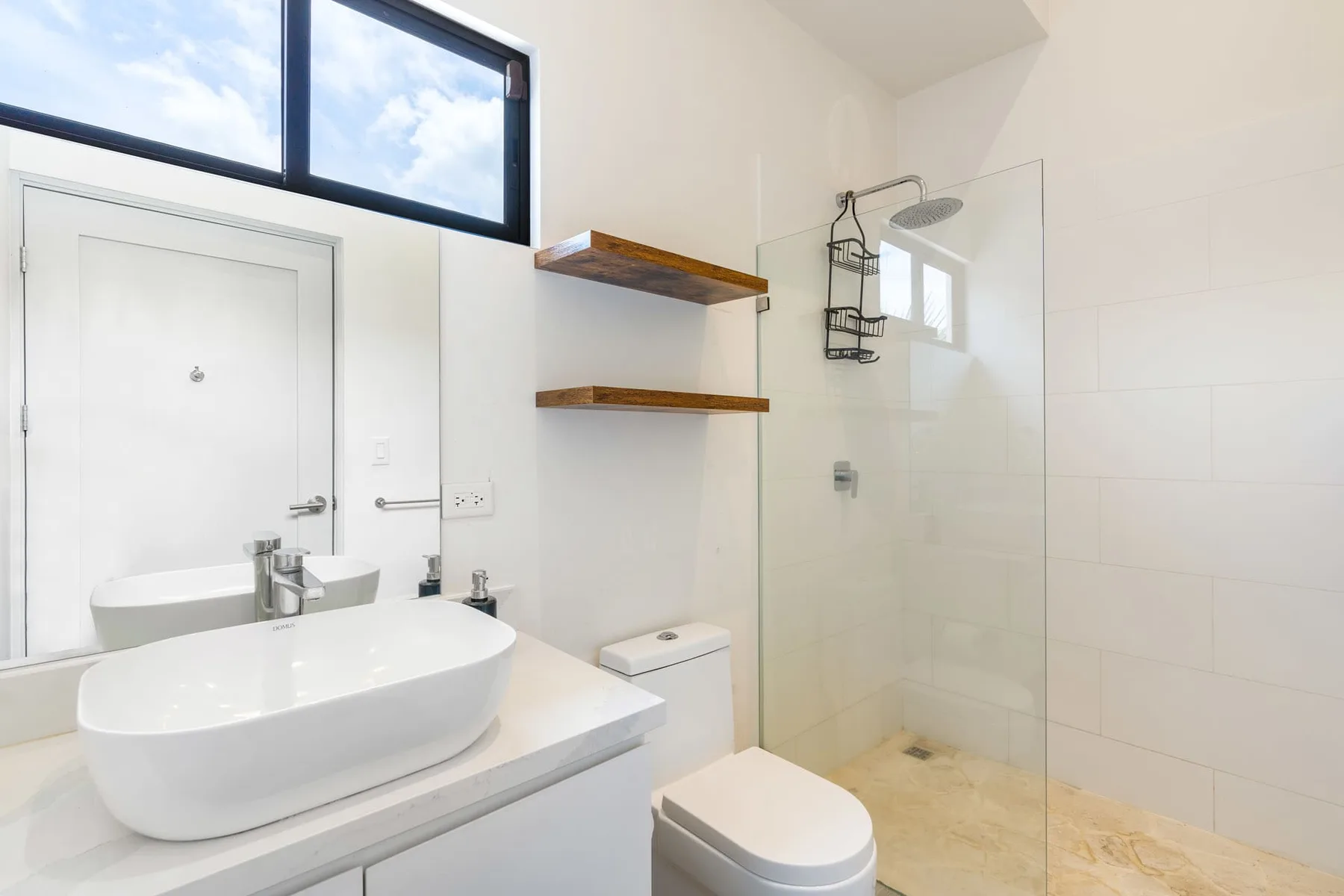 A bright bathroom with a sink, toilet, and glass shower.