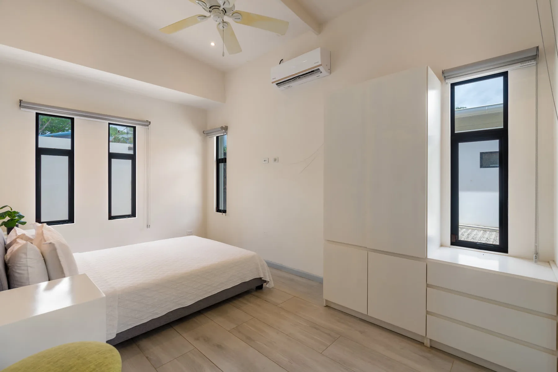 A bedroom with a bed, built-in storage, and windows.