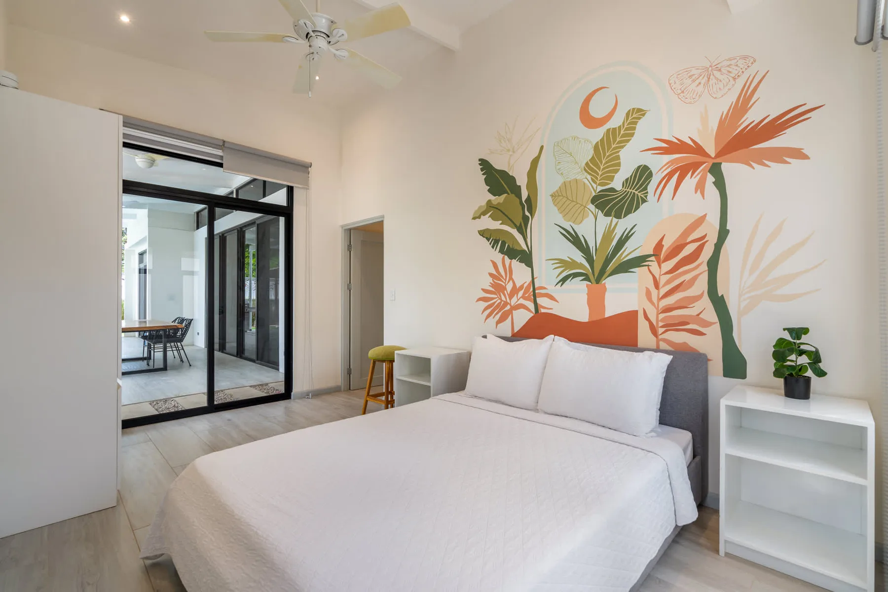 A bedroom with a bed beneath a colorful botanical wall mural.