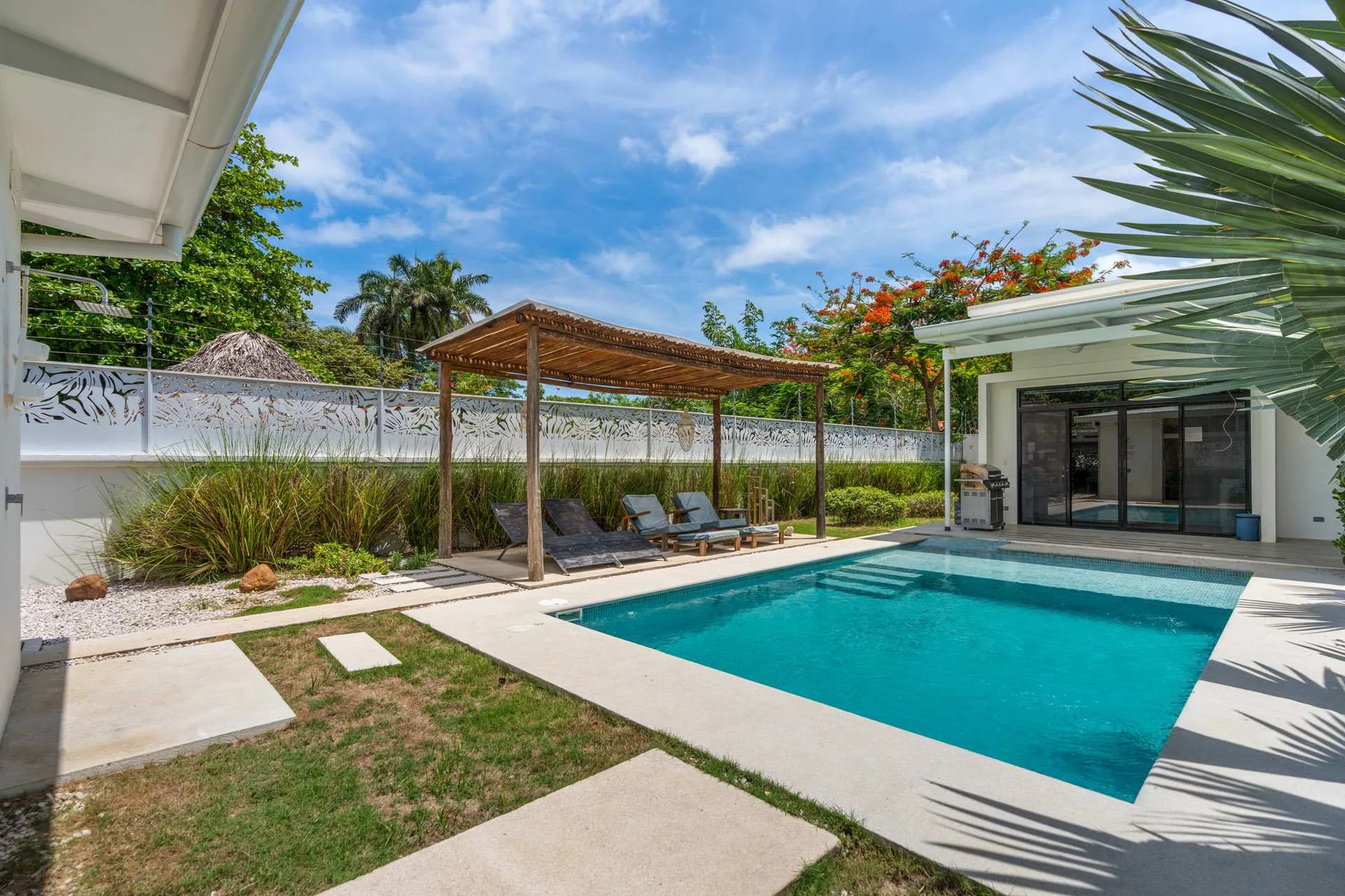 An outdoor swimming pool beside a shaded seating area and modern building.