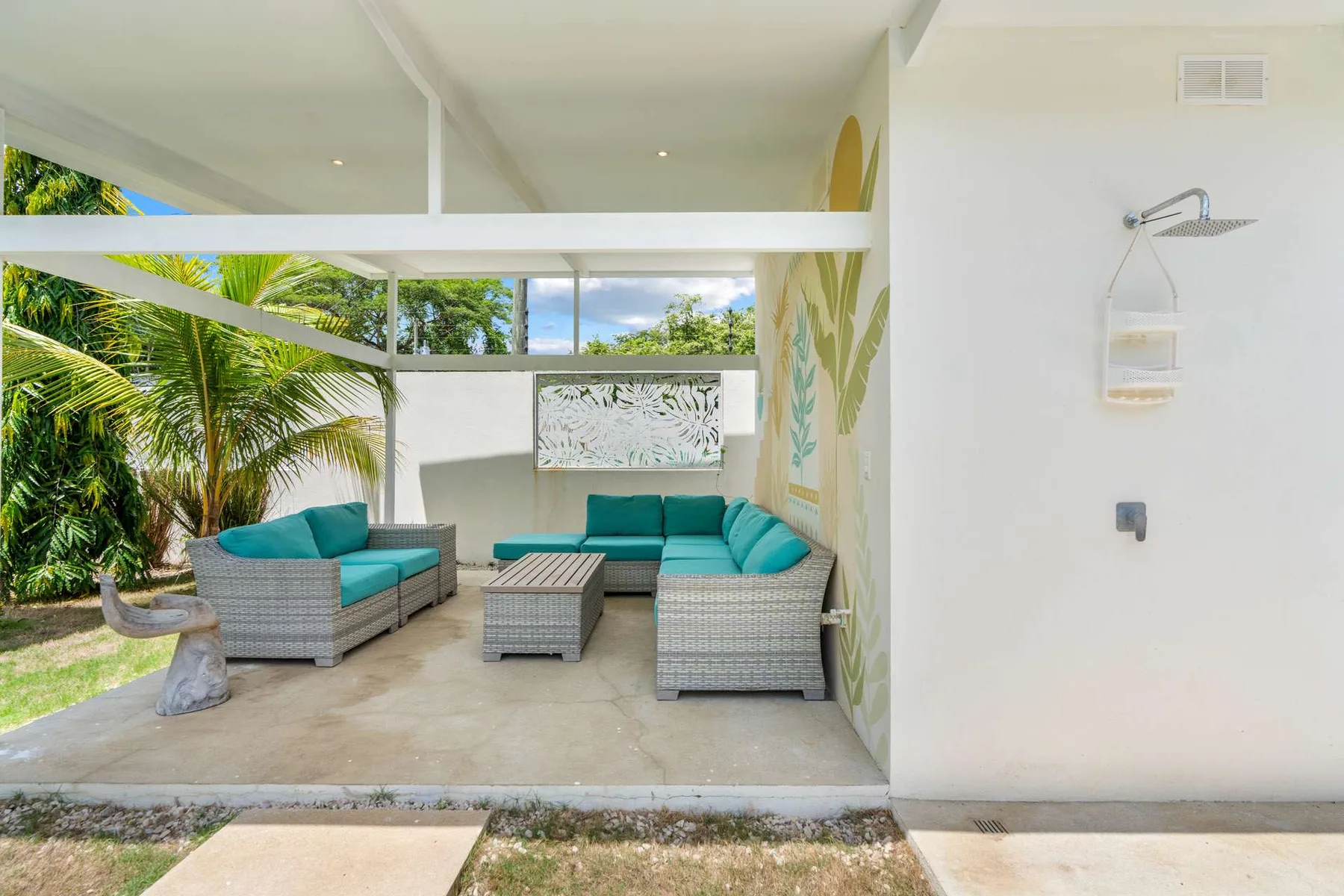 An open-air patio seating area with teal cushions and tropical greenery.