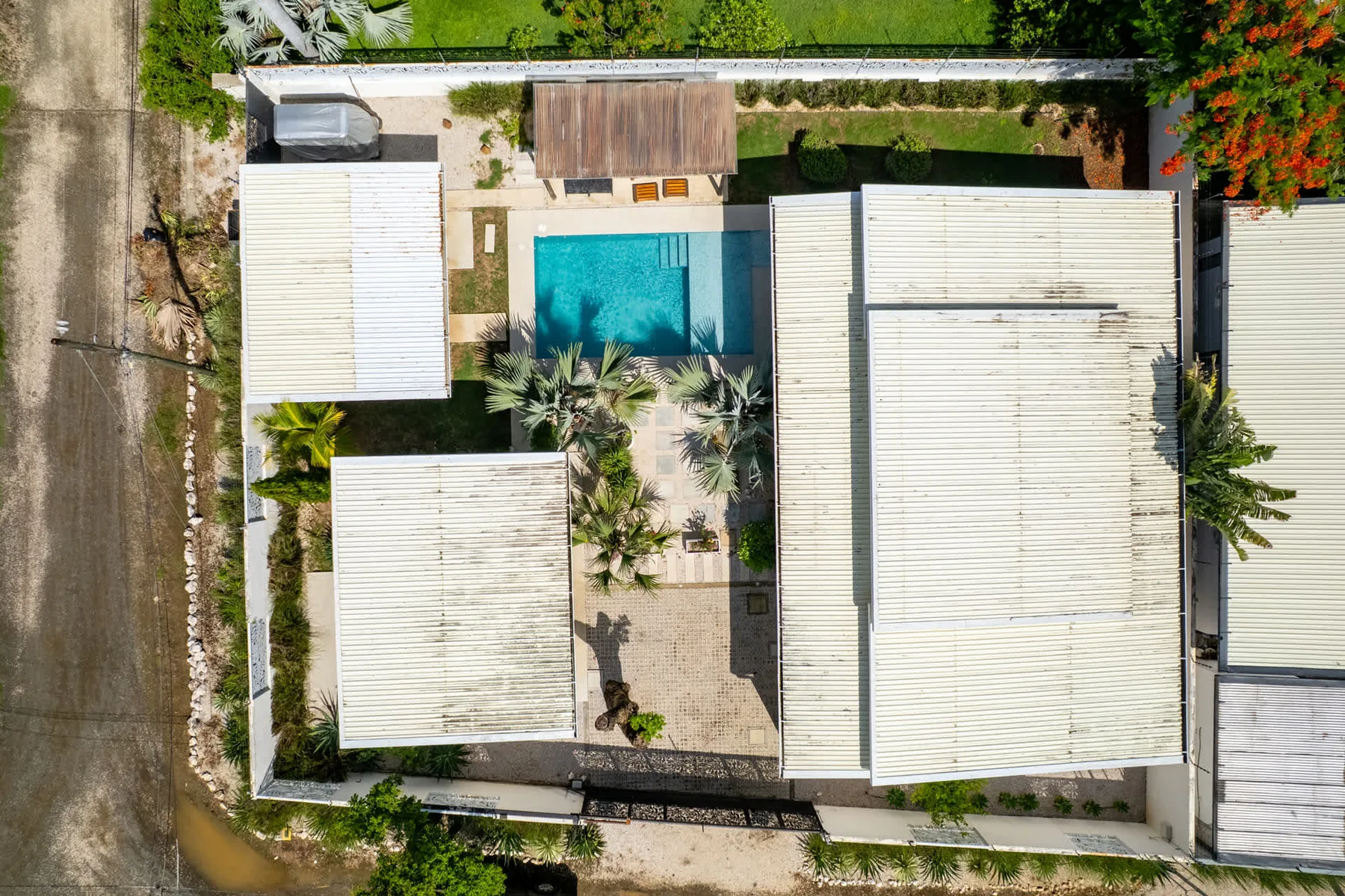 An aerial view of a property with white-roofed buildings surrounding a swimming pool.