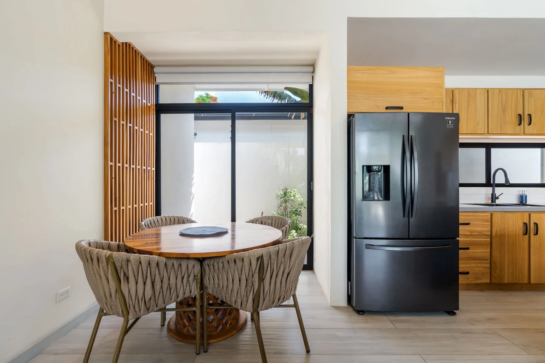 A dining area with a round table and seating beside an open kitchen.