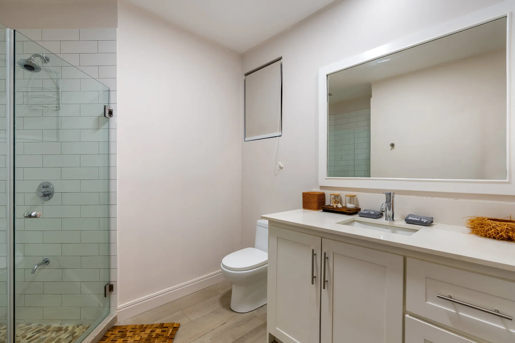 Un baño con ducha de vidrio, inodoro y tocador bajo un espejo grande.