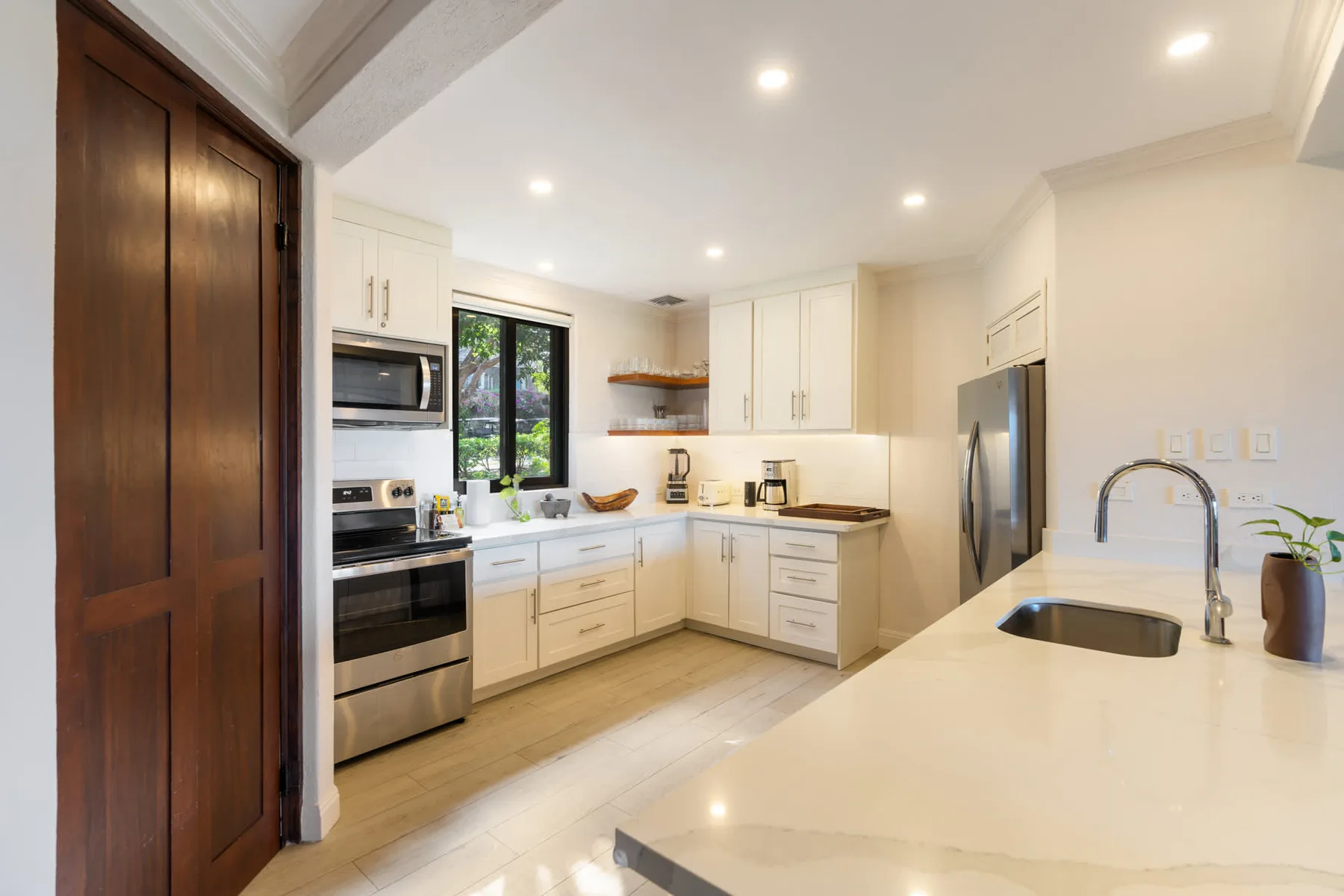 Una cocina luminosa con gabinetes blancos, electrodomésticos de acero inoxidable y una isla amplia.