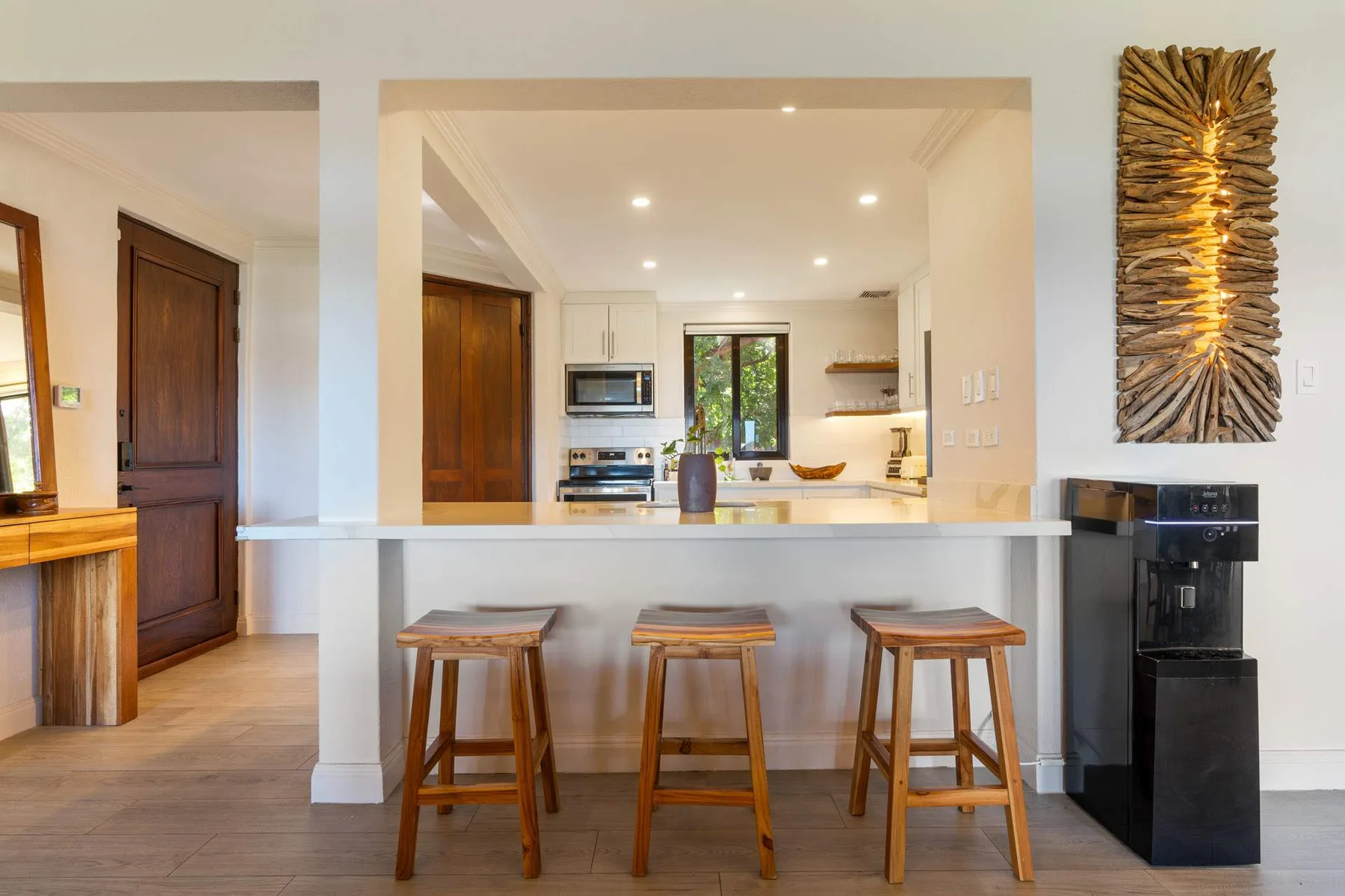 Una cocina luminosa con una barra blanca y taburetes de madera.