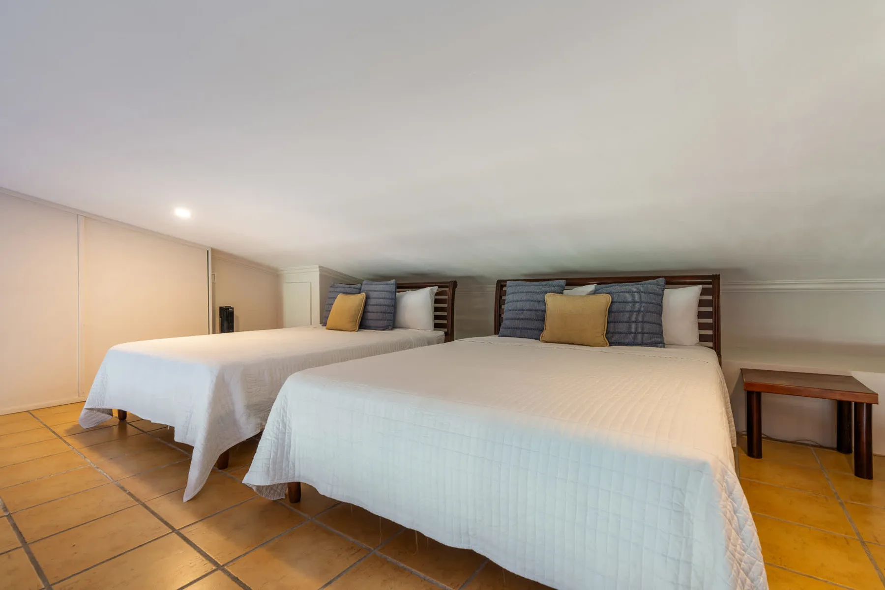 Un dormitorio con dos camas, ambas vestidas con ropa de cama clara.