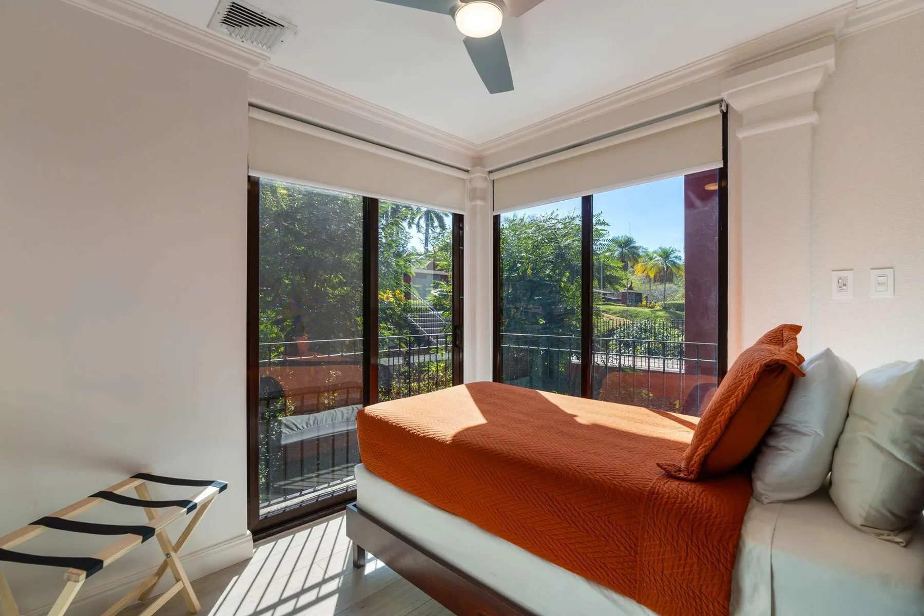 Un dormitorio con una cama junto a grandes ventanas con vista a la vegetación.
