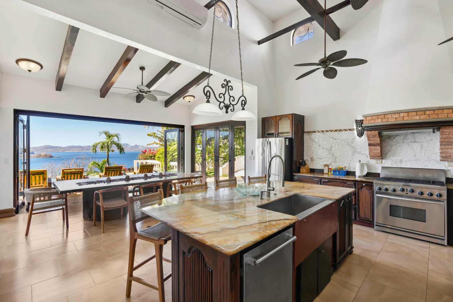 A spacious kitchen and dining area opens onto a waterfront view through large windows.