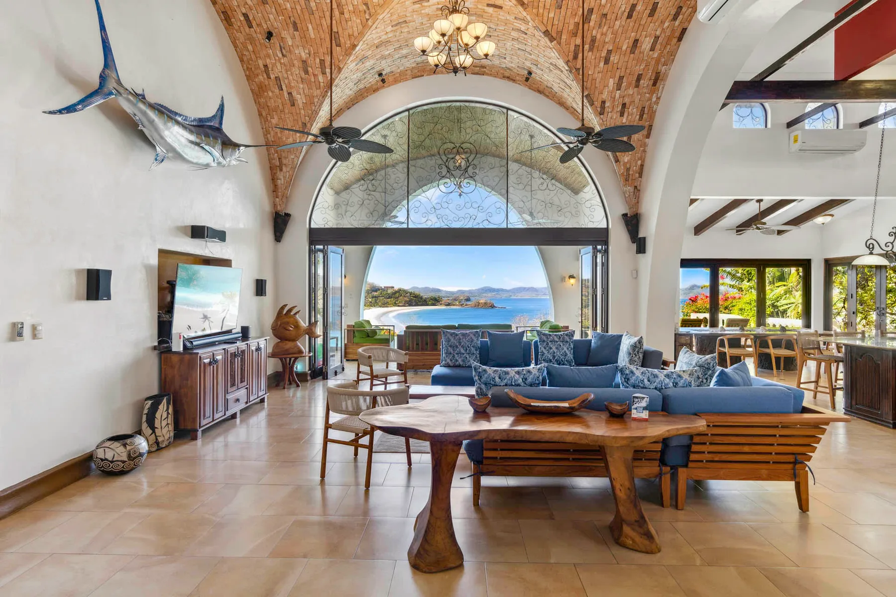 A spacious living room opens onto a view of the sea through large windows.