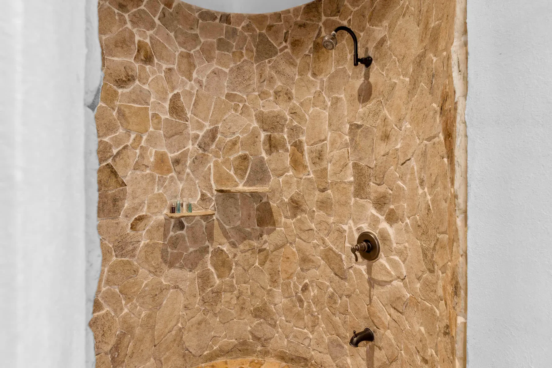 A stone-tiled shower area with dark metal shower fixtures.