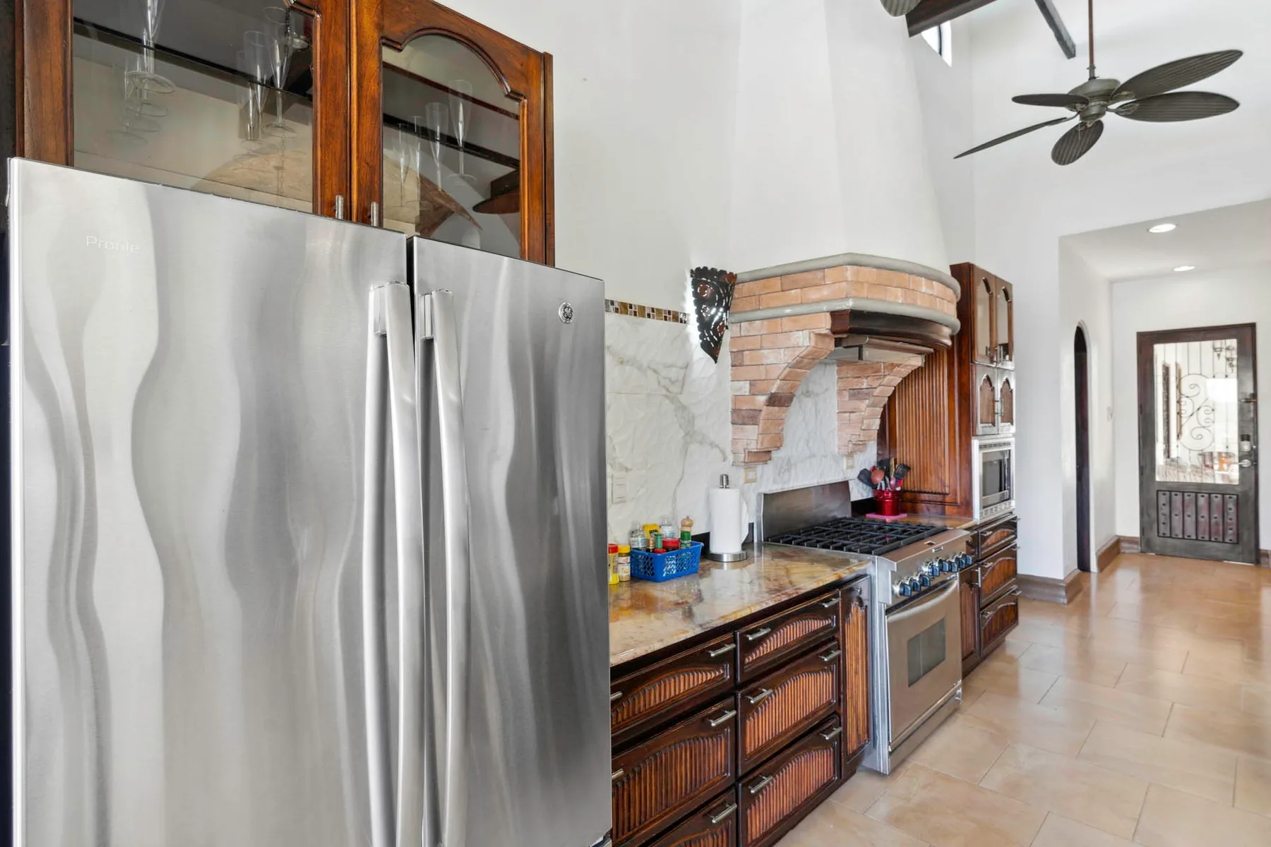 A kitchen with stainless steel appliances and a brick cooking alcove.