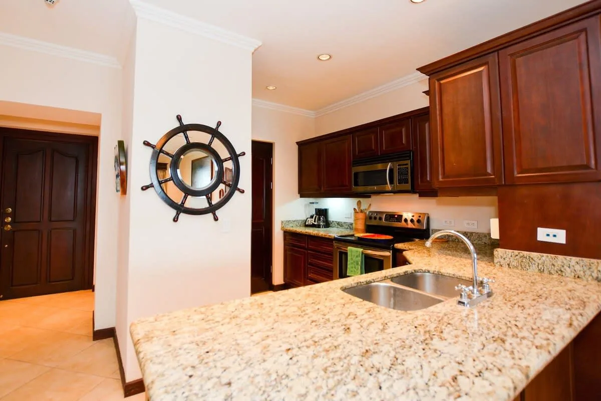 A kitchen with dark wood cabinets, stainless steel appliances, and a stone countertop.