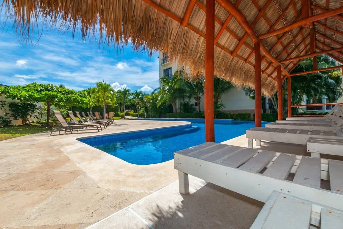 Shared amenity: A swimming pool beside a thatched-roof seating area.