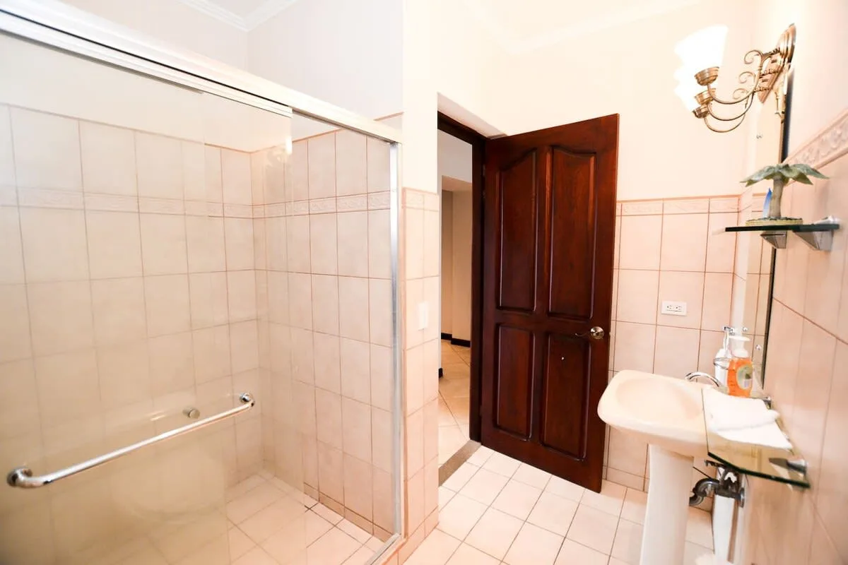 A tiled bathroom with a glass shower and an open wooden door.