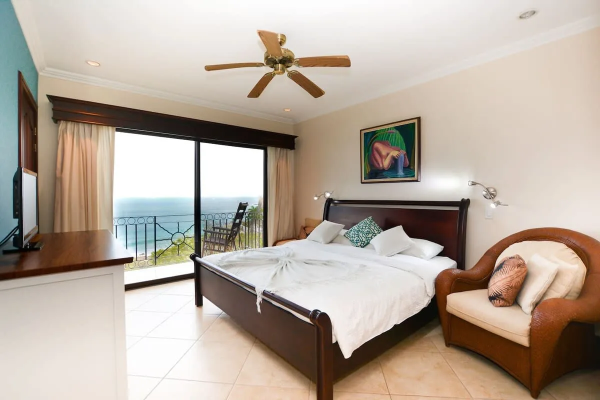 A bedroom with a bed beside a sliding glass door opening onto a balcony.