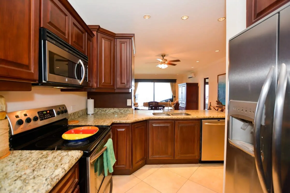 A kitchen with dark wood cabinets, granite countertops, and stainless steel appliances.