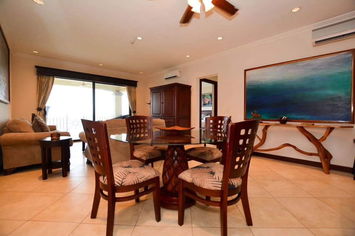 A dining area with wooden seating and a large framed painting on the wall.