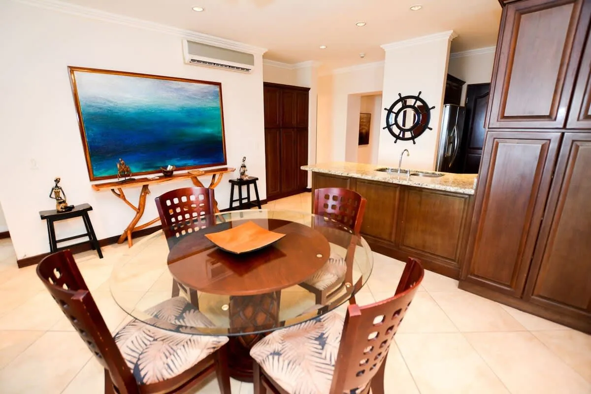A dining area with a round glass table and chairs beside a kitchen counter.
