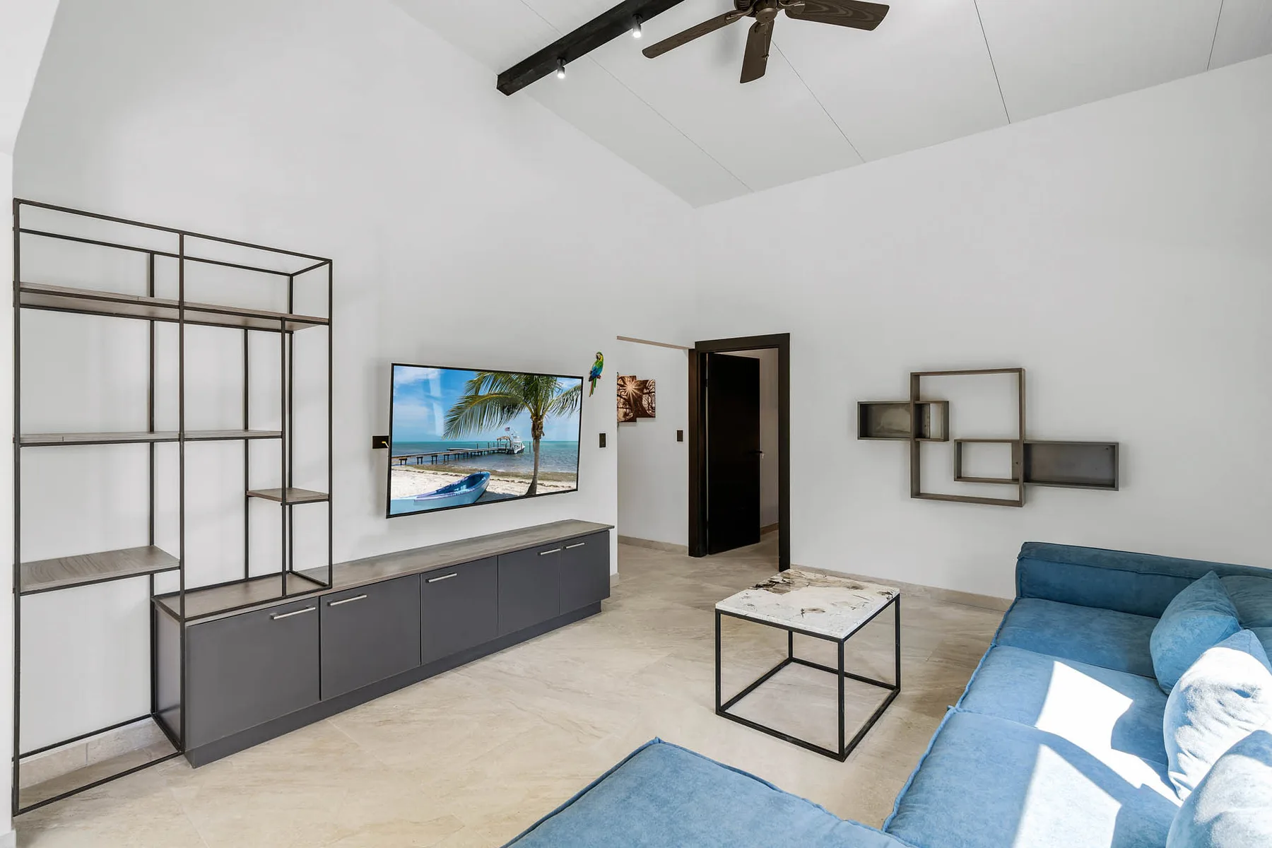 A bright living room with a blue seating area and wall-mounted television.