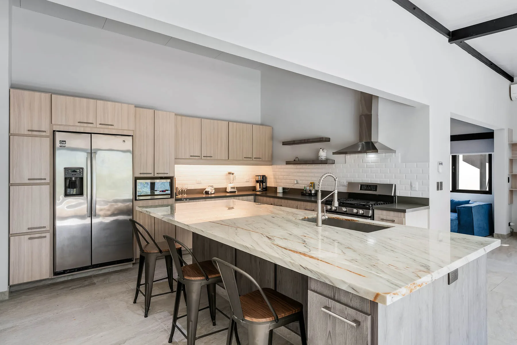 A modern kitchen with light wood cabinets and a large island with seating.