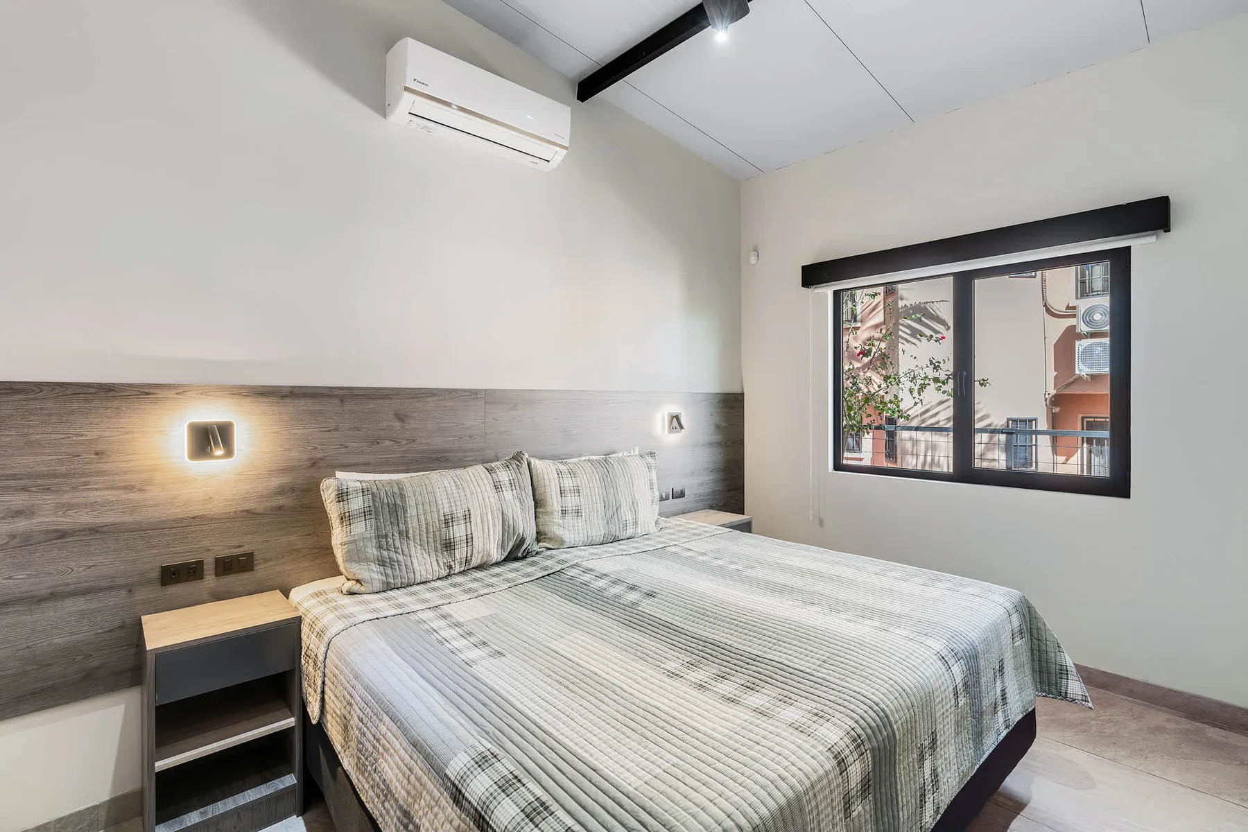 A bedroom with a neatly made bed beside a large window.
