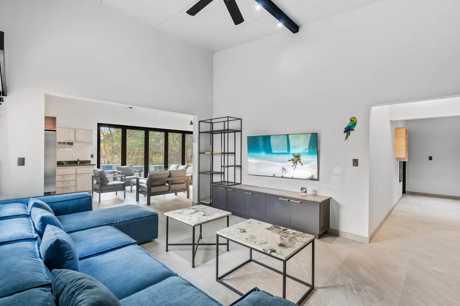 A bright living room with blue seating, coffee tables, and a television.