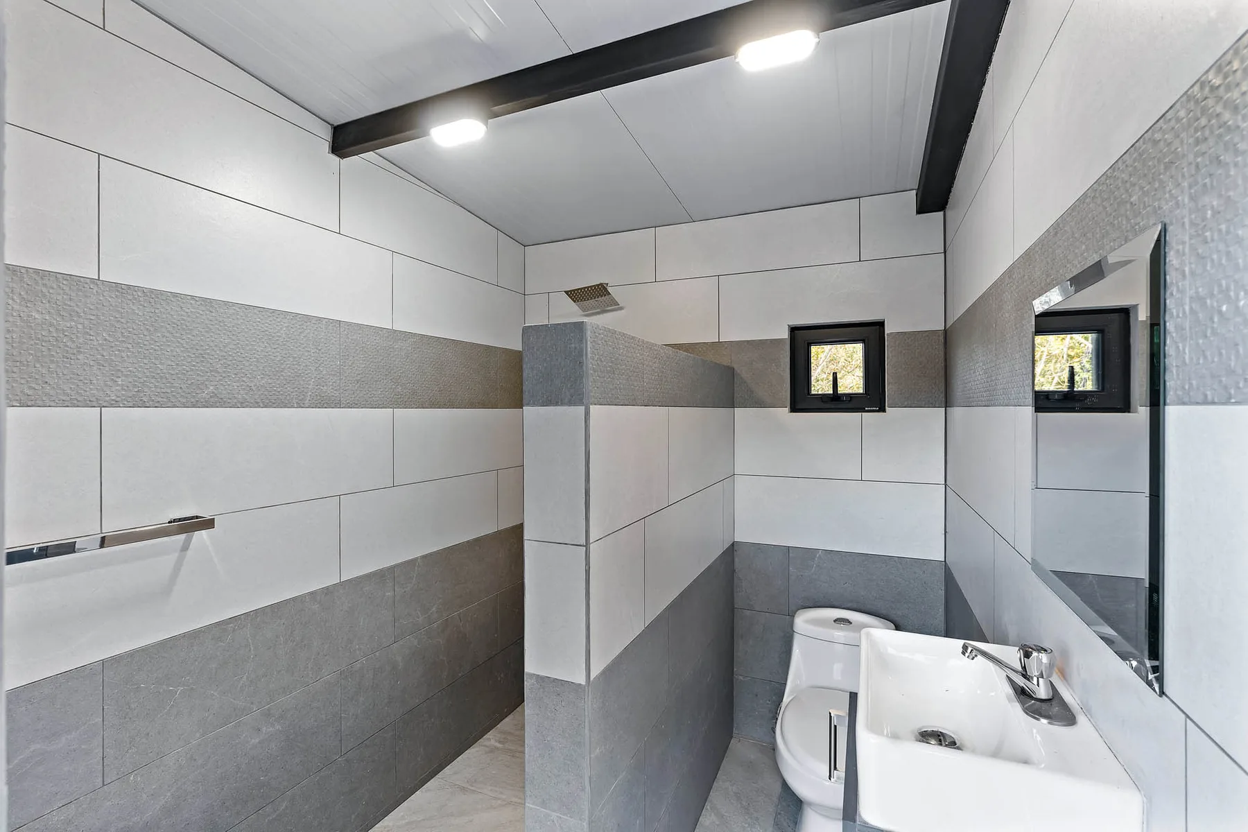 A tiled bathroom with a shower area, toilet, and sink.