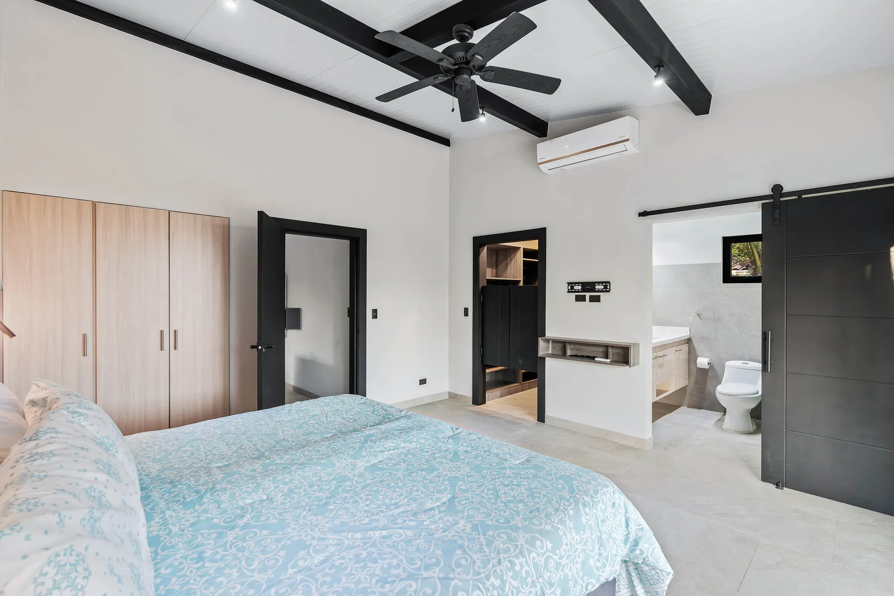 A bright bedroom with a bed, built-in wardrobes, and an attached bathroom.