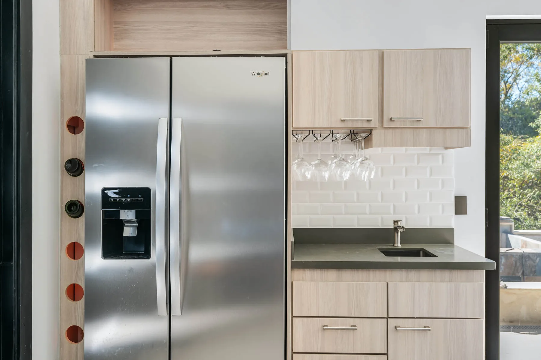 A kitchen with a stainless-steel refrigerator, cabinets, and a sink.
