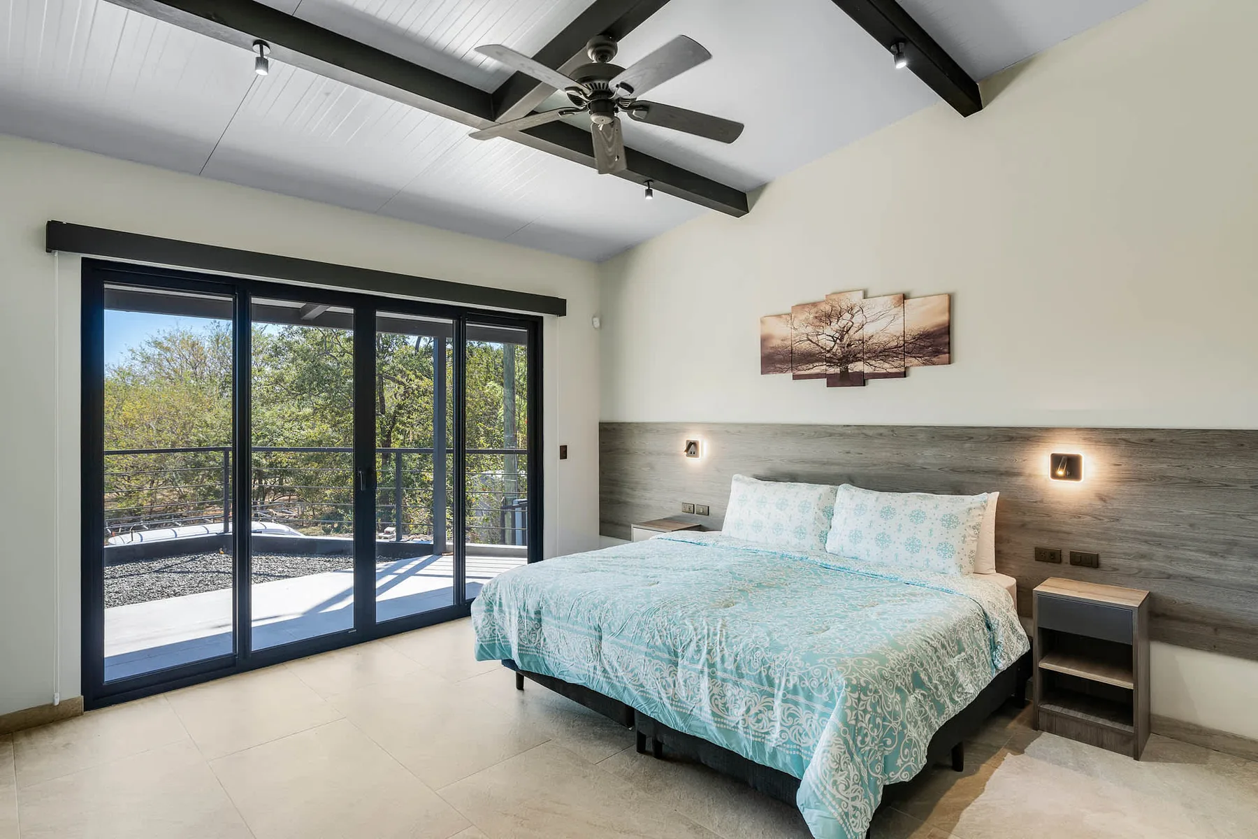 A bedroom with a bed beside large glass doors opening onto a balcony.