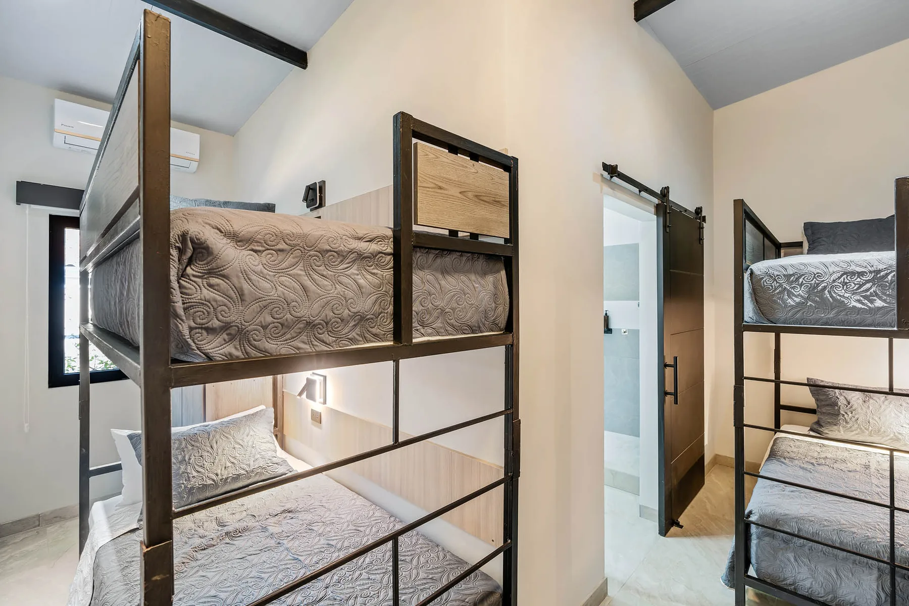 A bedroom with two metal bunk beds and gray patterned bedding.