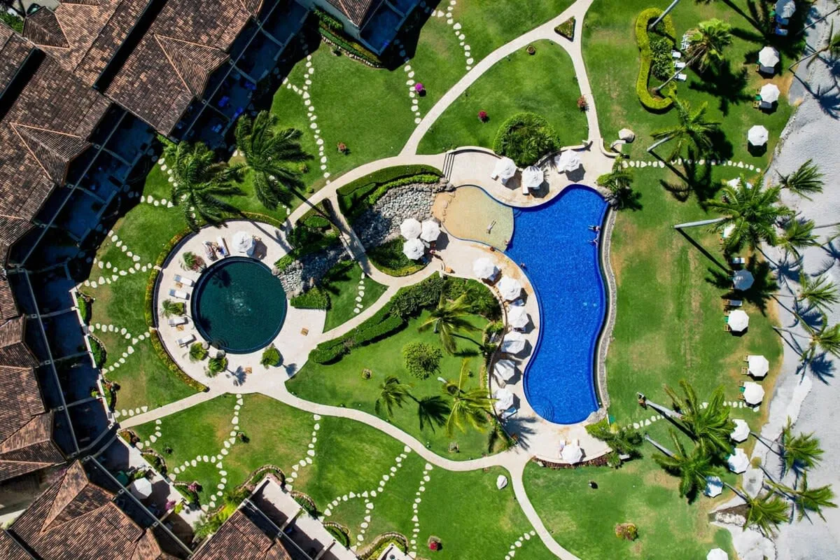Zona común: Zona de piscinas al aire libre con caminos sinuosos y vegetación alrededor.